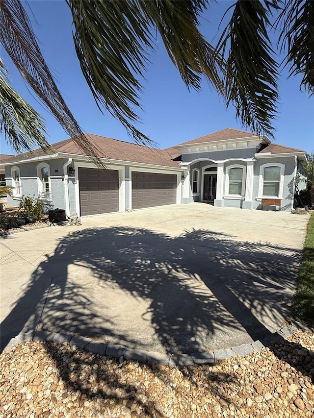 view of front of home with driveway, an attached garage, and stucco siding