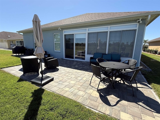 rear view of house with a yard, roof with shingles, a patio area, and stucco siding