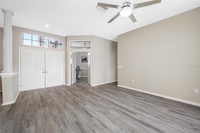 unfurnished bedroom with baseboards, visible vents, ornate columns, and wood finished floors