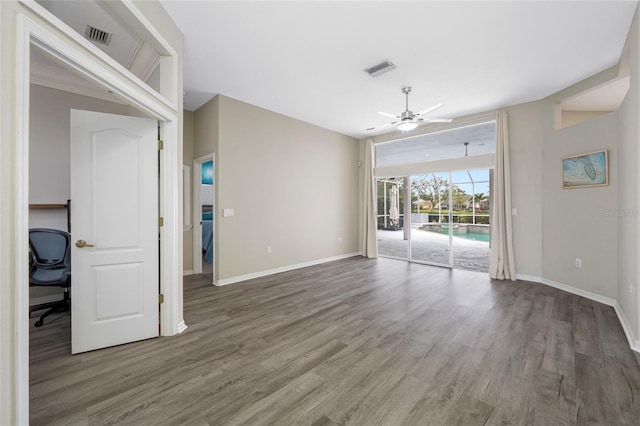 empty room with wood finished floors, visible vents, and baseboards