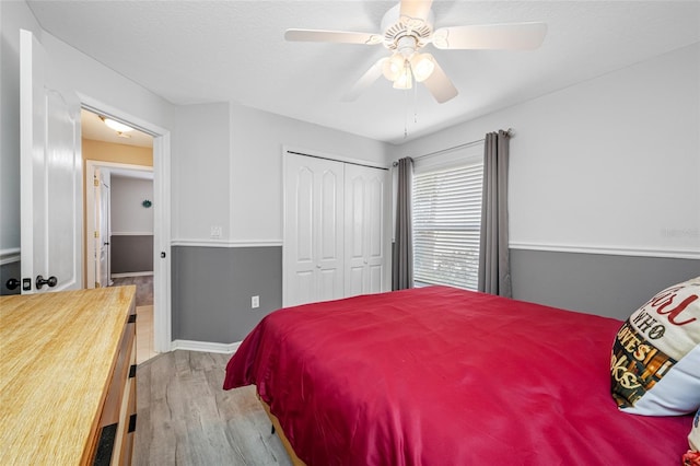 bedroom with ceiling fan, a closet, and light wood-style flooring