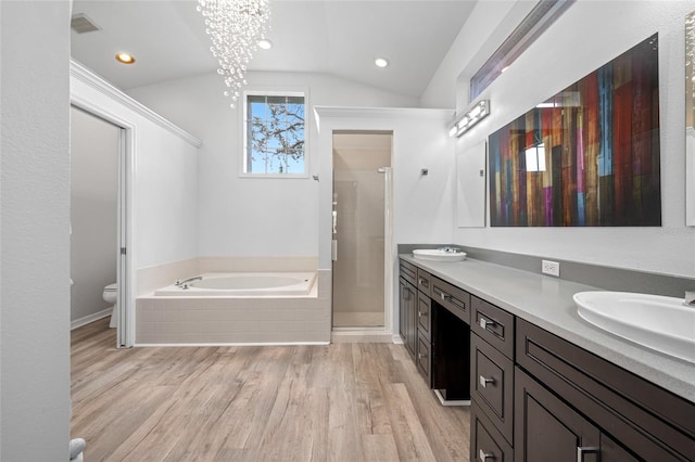 bathroom with a garden tub, toilet, wood finished floors, vaulted ceiling, and a stall shower