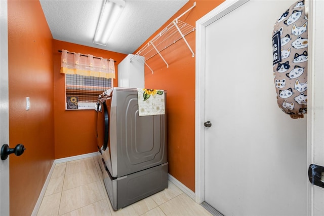 clothes washing area featuring washer / clothes dryer, laundry area, a textured ceiling, tile patterned flooring, and baseboards