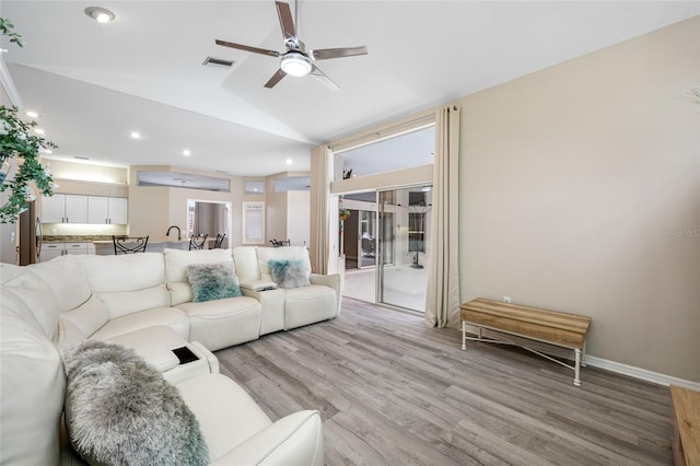 living room featuring light wood finished floors, visible vents, a ceiling fan, and vaulted ceiling