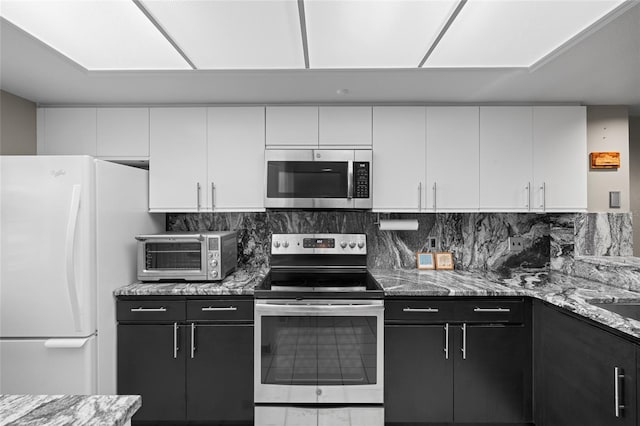 kitchen with dark cabinetry, a toaster, white cabinets, appliances with stainless steel finishes, and tasteful backsplash