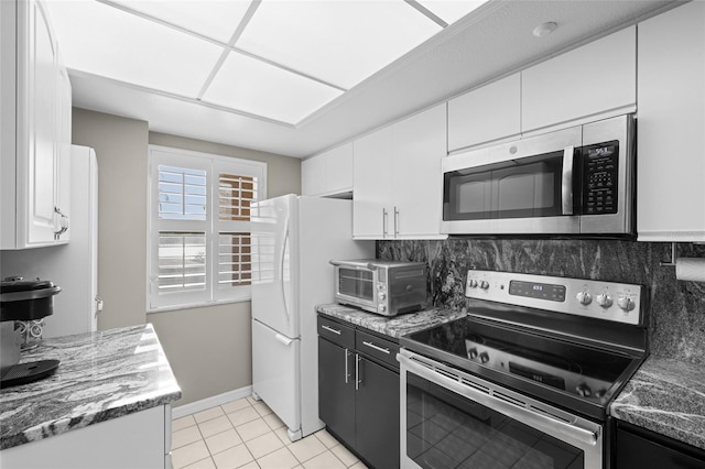 kitchen featuring backsplash, a toaster, light tile patterned floors, appliances with stainless steel finishes, and white cabinetry