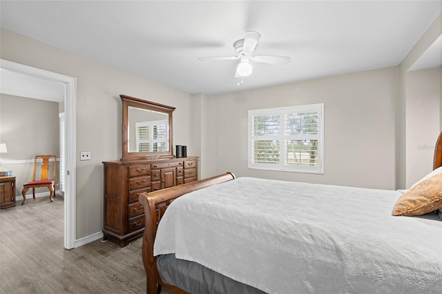 bedroom featuring baseboards, wood finished floors, and a ceiling fan