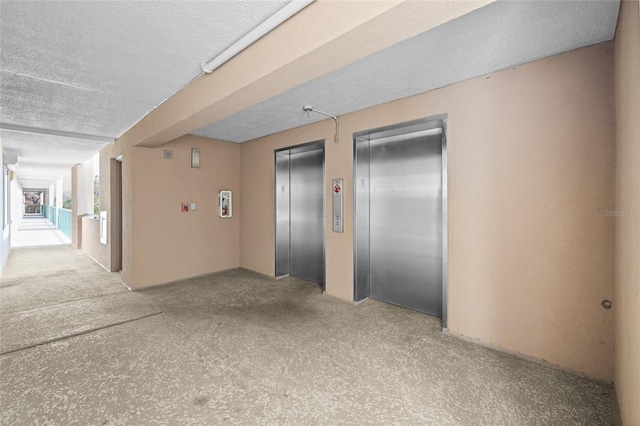 unfurnished room featuring elevator and a textured ceiling