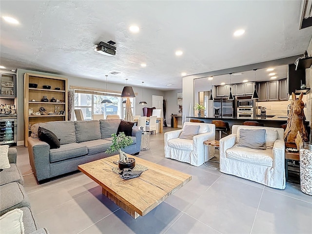 living room with recessed lighting, beverage cooler, a textured ceiling, and light tile patterned floors