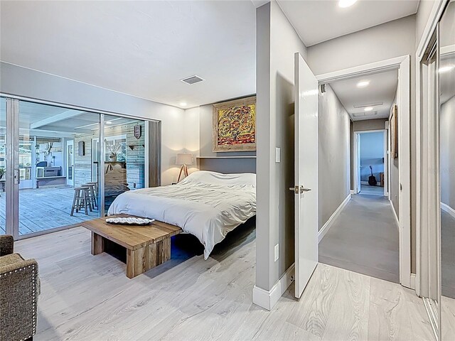 bedroom with access to exterior, visible vents, baseboards, and wood finished floors