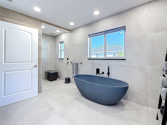 full bathroom with visible vents, a freestanding tub, tile walls, and recessed lighting