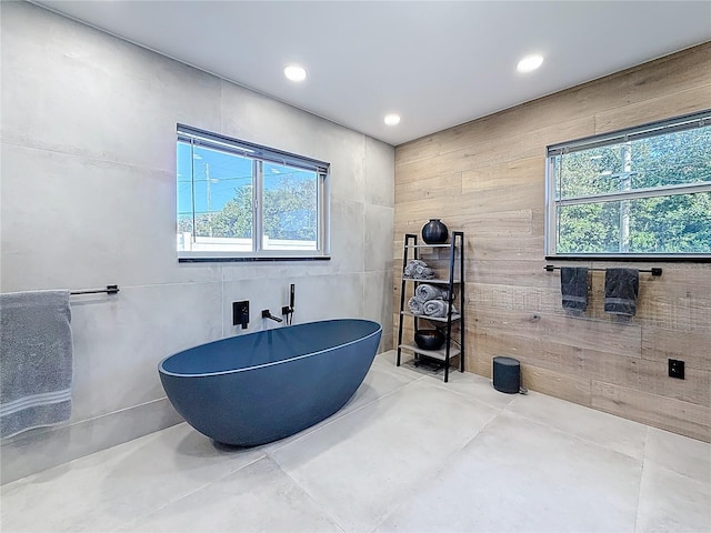 full bathroom with a healthy amount of sunlight, a freestanding tub, concrete flooring, and recessed lighting