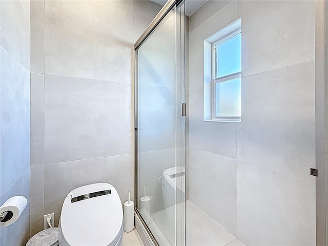 bathroom with tile walls, a shower stall, and toilet