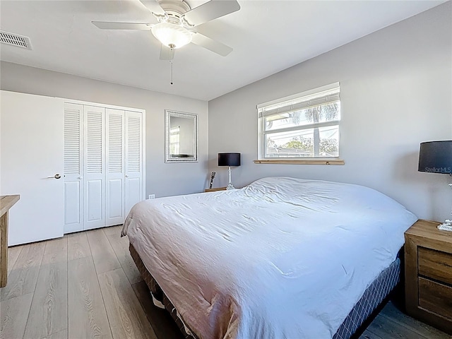 bedroom featuring a ceiling fan, a closet, visible vents, and wood finished floors