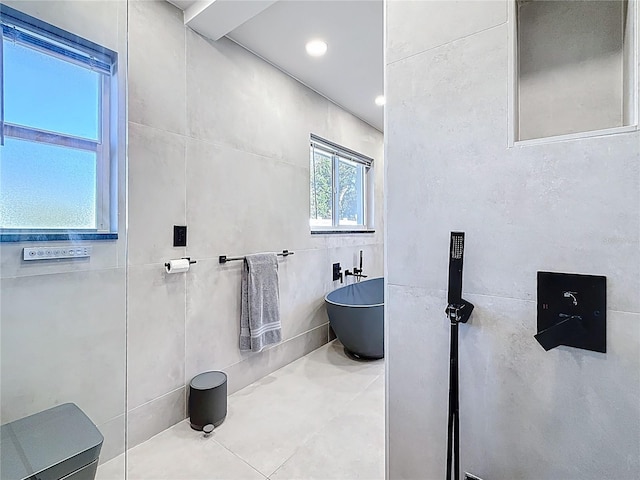 bathroom with a soaking tub and tile walls