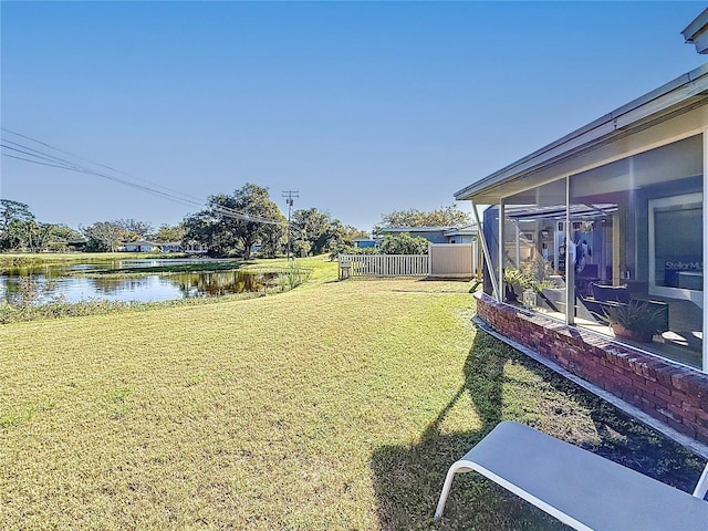 view of yard with a water view, a sunroom, and fence