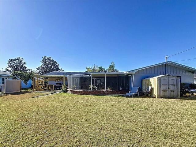 back of house with a shed, a lawn, an outdoor structure, and a sunroom