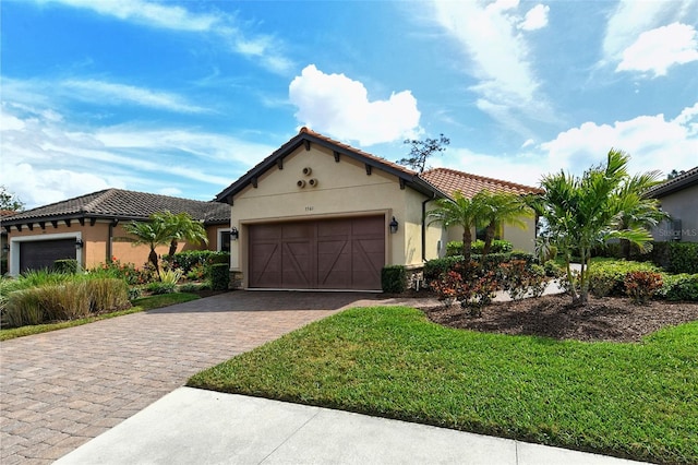 mediterranean / spanish house with a tiled roof, a front yard, stucco siding, decorative driveway, and a garage