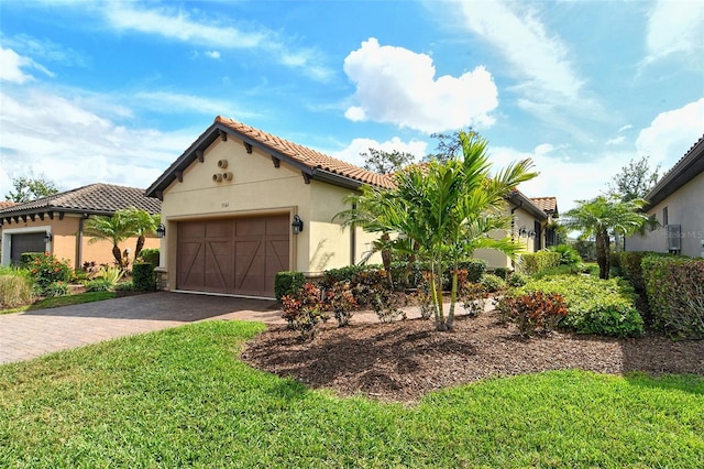 mediterranean / spanish house with stucco siding, a front lawn, decorative driveway, a garage, and a tiled roof