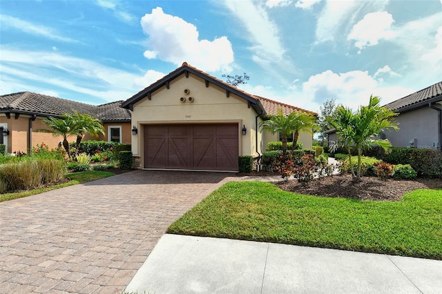 mediterranean / spanish-style home featuring a tiled roof, decorative driveway, an attached garage, and stucco siding