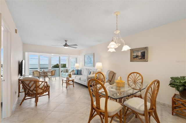 dining space with light tile patterned flooring, ceiling fan with notable chandelier, and baseboards