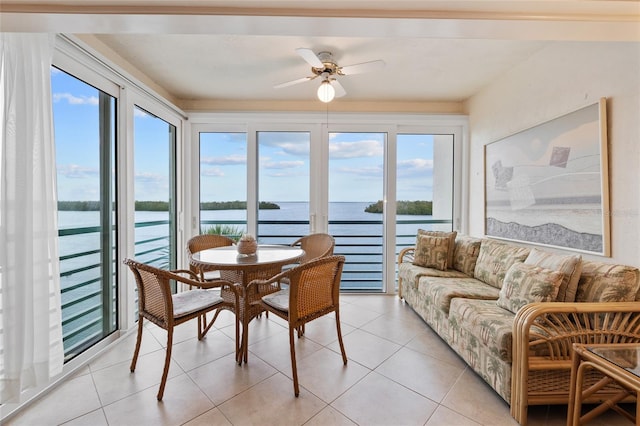 sunroom with a healthy amount of sunlight, a ceiling fan, and a water view