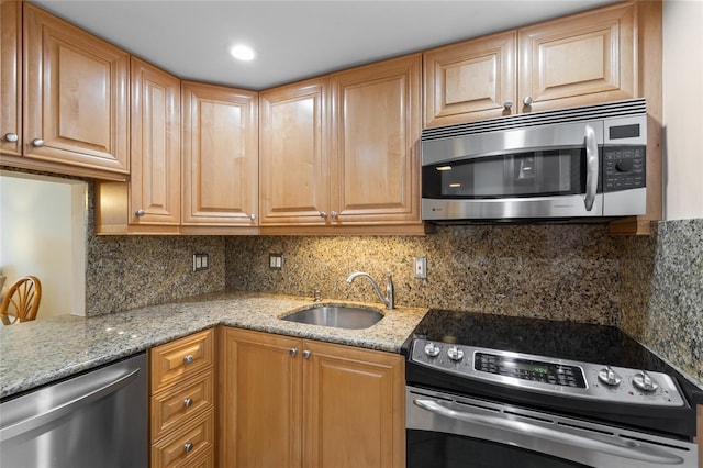 kitchen featuring tasteful backsplash, appliances with stainless steel finishes, light stone counters, and a sink