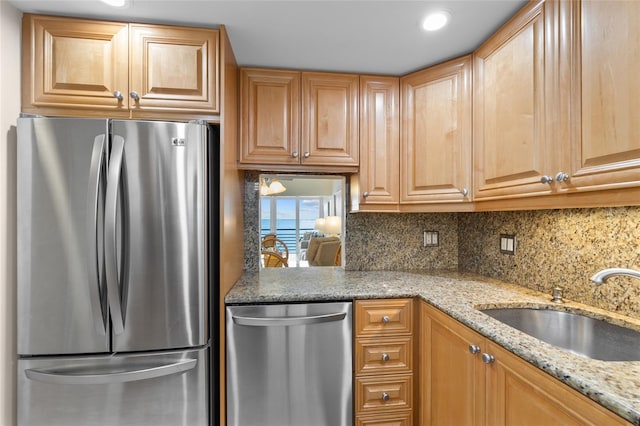 kitchen with light stone counters, decorative backsplash, stainless steel appliances, and a sink