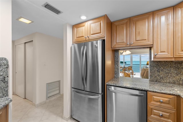 kitchen featuring decorative backsplash, light stone counters, visible vents, and stainless steel appliances