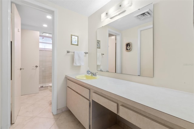 bathroom with vanity, visible vents, a tile shower, tile patterned flooring, and toilet