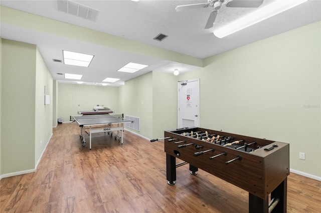 playroom with ceiling fan, visible vents, baseboards, and wood finished floors