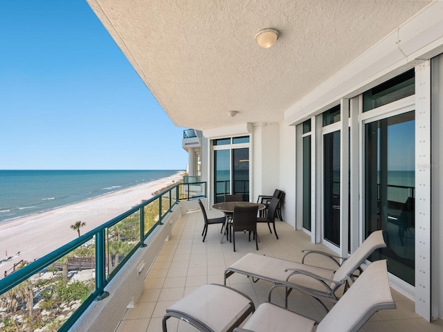 balcony featuring a water view, an AC wall unit, and a view of the beach