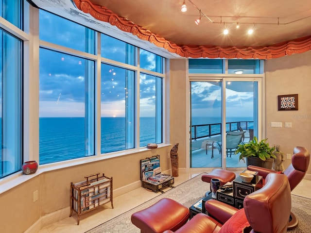 living area featuring tile patterned floors, baseboards, and a water view