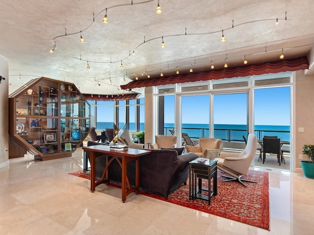 living room featuring floor to ceiling windows, a healthy amount of sunlight, rail lighting, and a water view