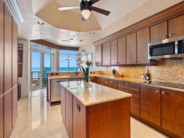 kitchen with a kitchen island, light stone counters, decorative backsplash, a peninsula, and stainless steel appliances