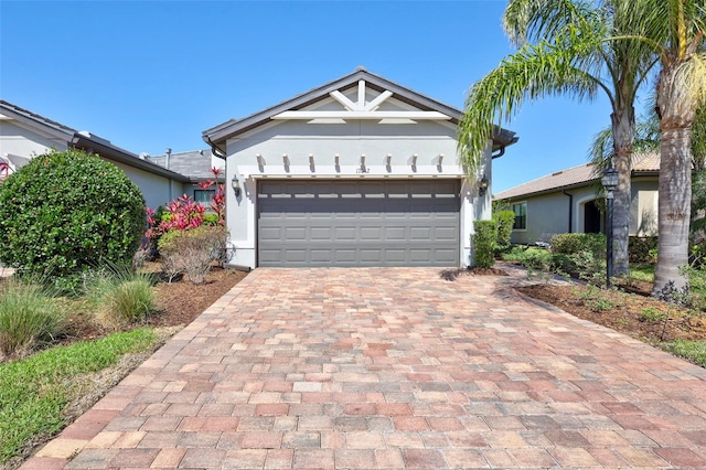 view of front facade featuring decorative driveway, an attached garage, and stucco siding