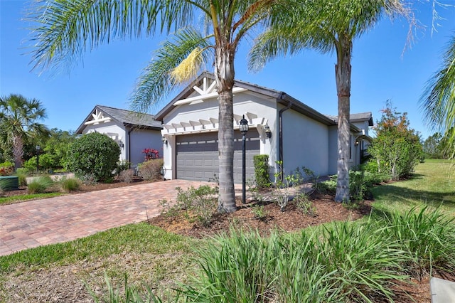 view of front of home with decorative driveway, an attached garage, and stucco siding