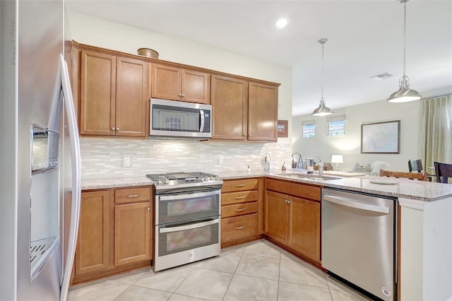 kitchen with a peninsula, appliances with stainless steel finishes, a sink, and tasteful backsplash