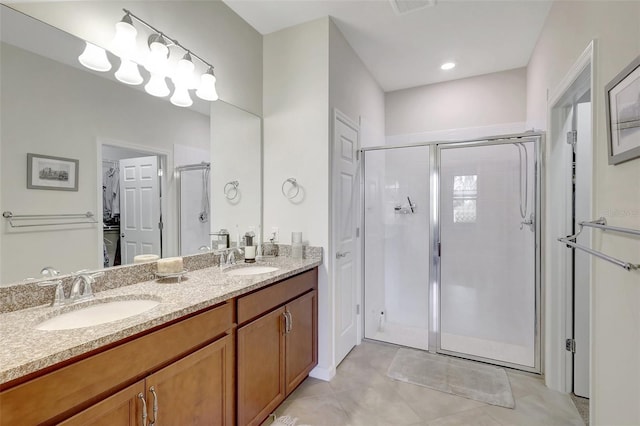 full bath featuring double vanity, a sink, a walk in closet, and a shower stall