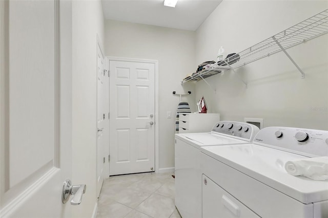 laundry room with laundry area, washer and clothes dryer, and light tile patterned floors