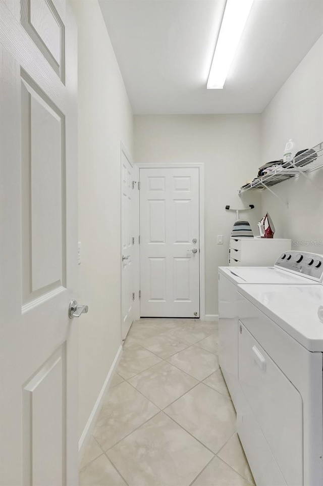 laundry room featuring light tile patterned floors, laundry area, washing machine and dryer, and baseboards