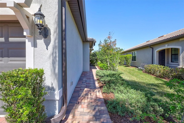 view of home's exterior with a garage, a lawn, and stucco siding