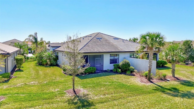 view of front of property with a front yard, a tile roof, and stucco siding