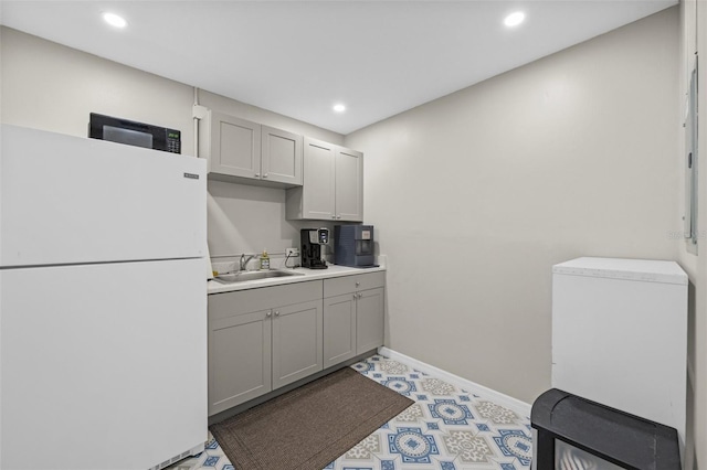 kitchen with gray cabinetry, recessed lighting, freestanding refrigerator, refrigerator, and a sink