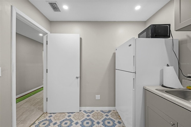 kitchen with visible vents, baseboards, black microwave, recessed lighting, and freestanding refrigerator