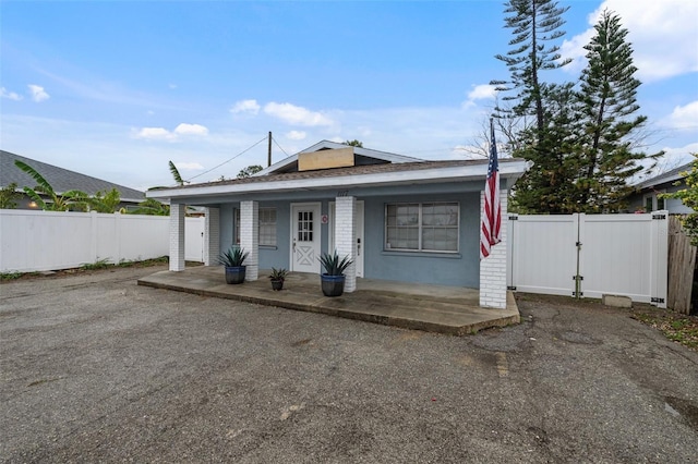 bungalow-style home featuring a gate, brick siding, covered porch, and fence