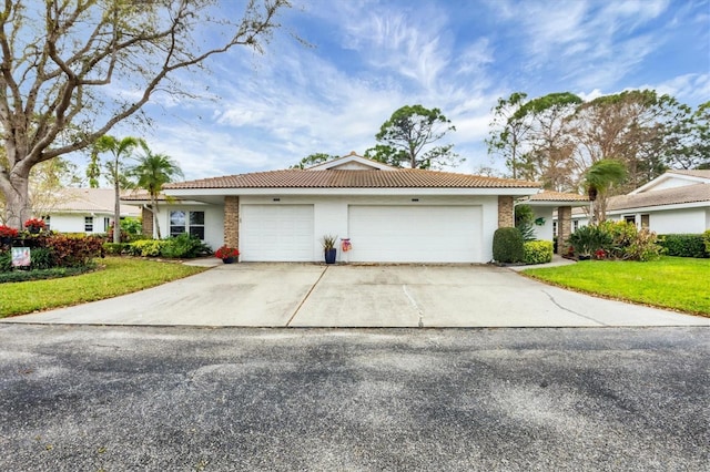 single story home with driveway, an attached garage, a tile roof, and a front lawn