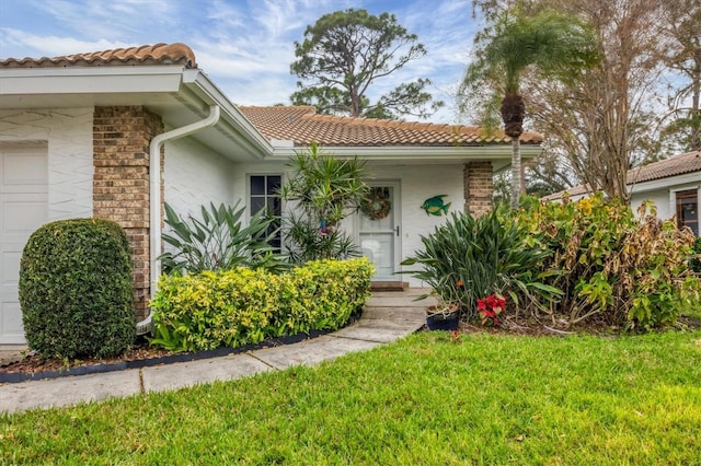 5614 Garden Lakes Dr, Bradenton, FL 34203 - view of front facade featuring a garage, a tile roof, brick siding, and a front yard