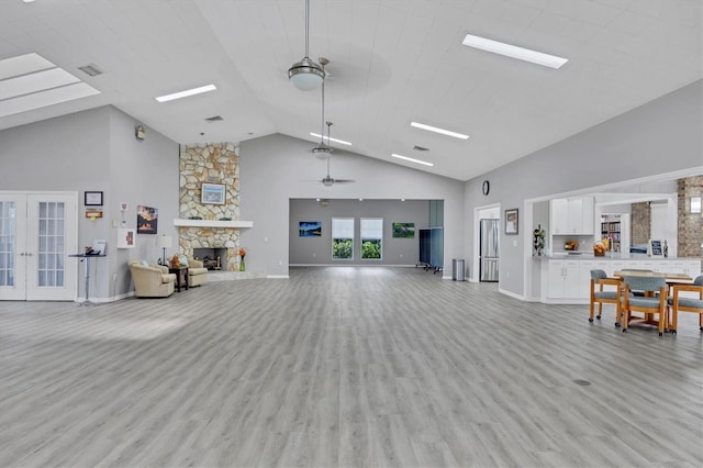 5614 Garden Lakes Dr, Bradenton, FL 34203 - living room featuring light wood finished floors, ceiling fan, a fireplace, and french doors