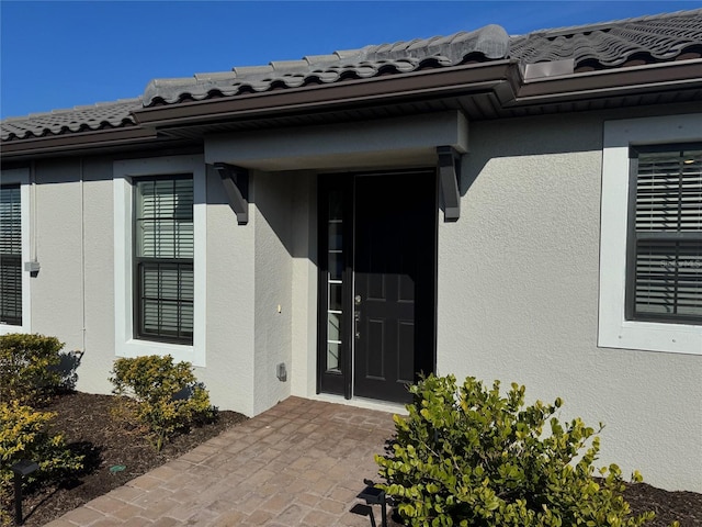 property entrance with a tile roof and stucco siding